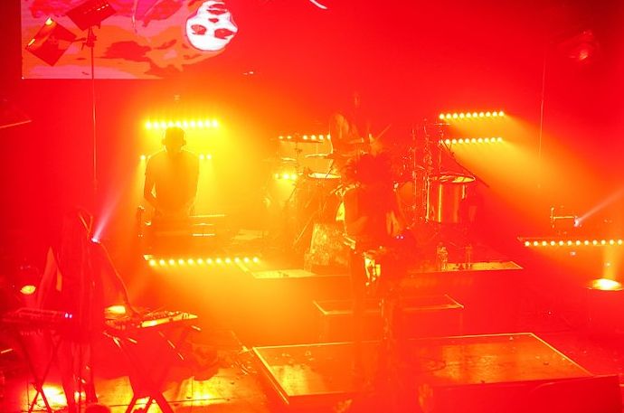Foto de concierto atmosférico de un escenario iluminado con luz roja y amarilla