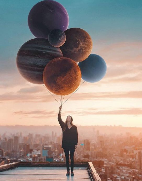 Fotografía artística de una niña sosteniendo planetas como globos.