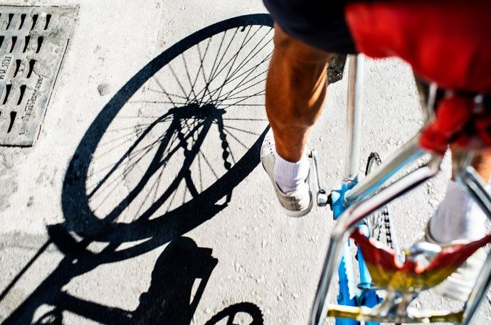 Un primer plano de un ciclista pedaleando con sombras en el suelo de piedra, el mejor momento del día para las fotos