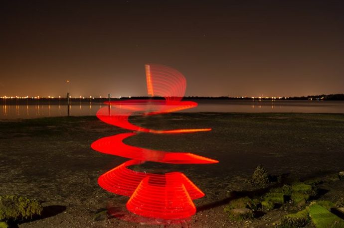 Una foto en espiral con luz roja en una playa por la noche.