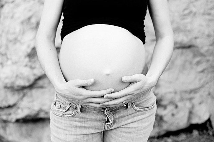 Retrato en blanco y negro de una mujer embarazada sosteniendo su vientre
