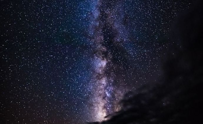 El cielo nocturno con la Vía Láctea apareciendo verticalmente