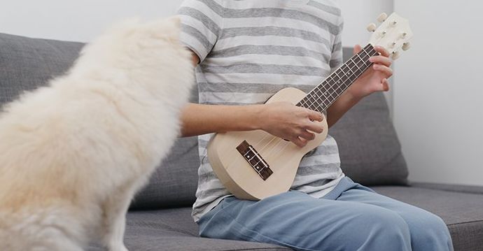 La dueña de una mascota toca el ukelele con su perro.