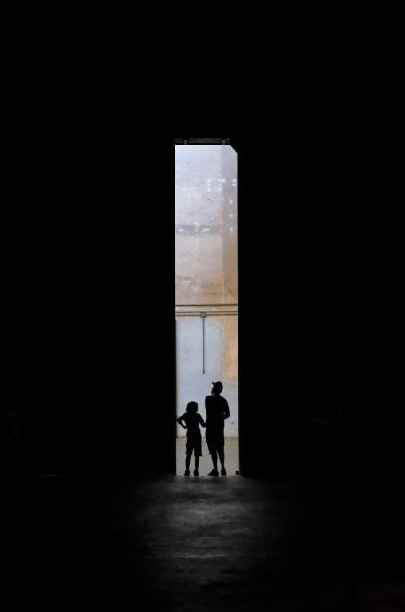 Una fotografía aérea de las siluetas de un hombre y un niño parados en un portal oscuro.