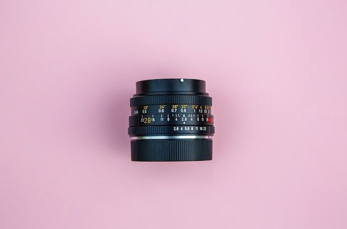 Fotografía cenital de una lente de cámara sobre un fondo rosa: la mejor lente para fotografía de productos