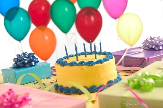 Foto de producto de naturaleza muerta de un pastel de cumpleaños, globos, regalos de cumpleaños envueltos en papel de diferentes colores y serpentinas de fiesta