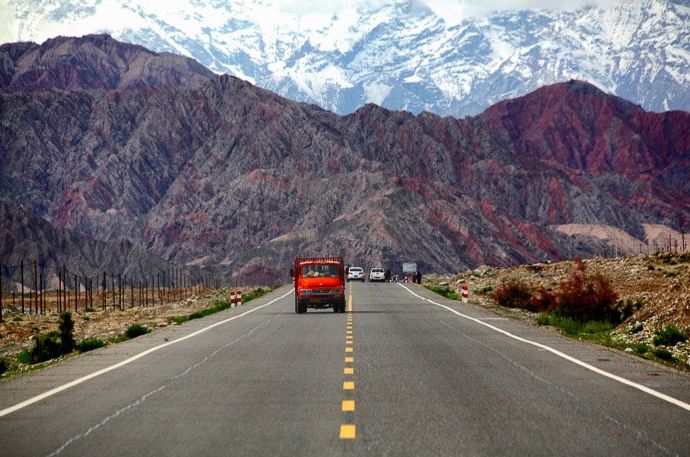 un camión rojo circulando por una carretera, precioso; Paisaje de montaña al fondo - planificación espacial en fotografía