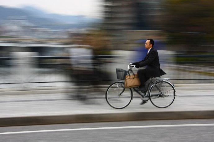 Un hombre montando una bicicleta en un paisaje urbano con un fondo borroso en movimiento - regla de la fotografía espacial