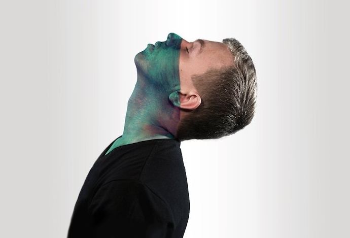Retrato surrealista de un hombre con un paño verde que cubre la mitad de su rostro mirando hacia arriba